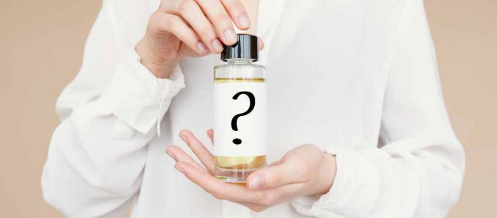 Person holding a small bottle with a question mark on the label, suggesting mystery or unknown contents.