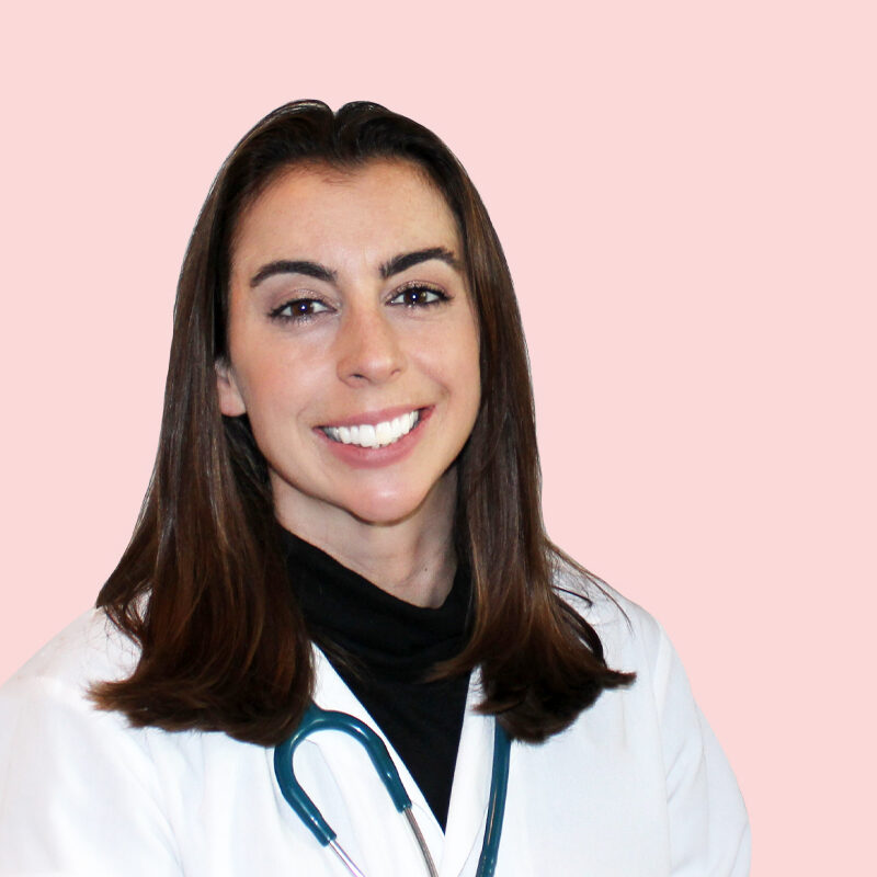 A person wearing a white coat and stethoscope smiles against a pink background.